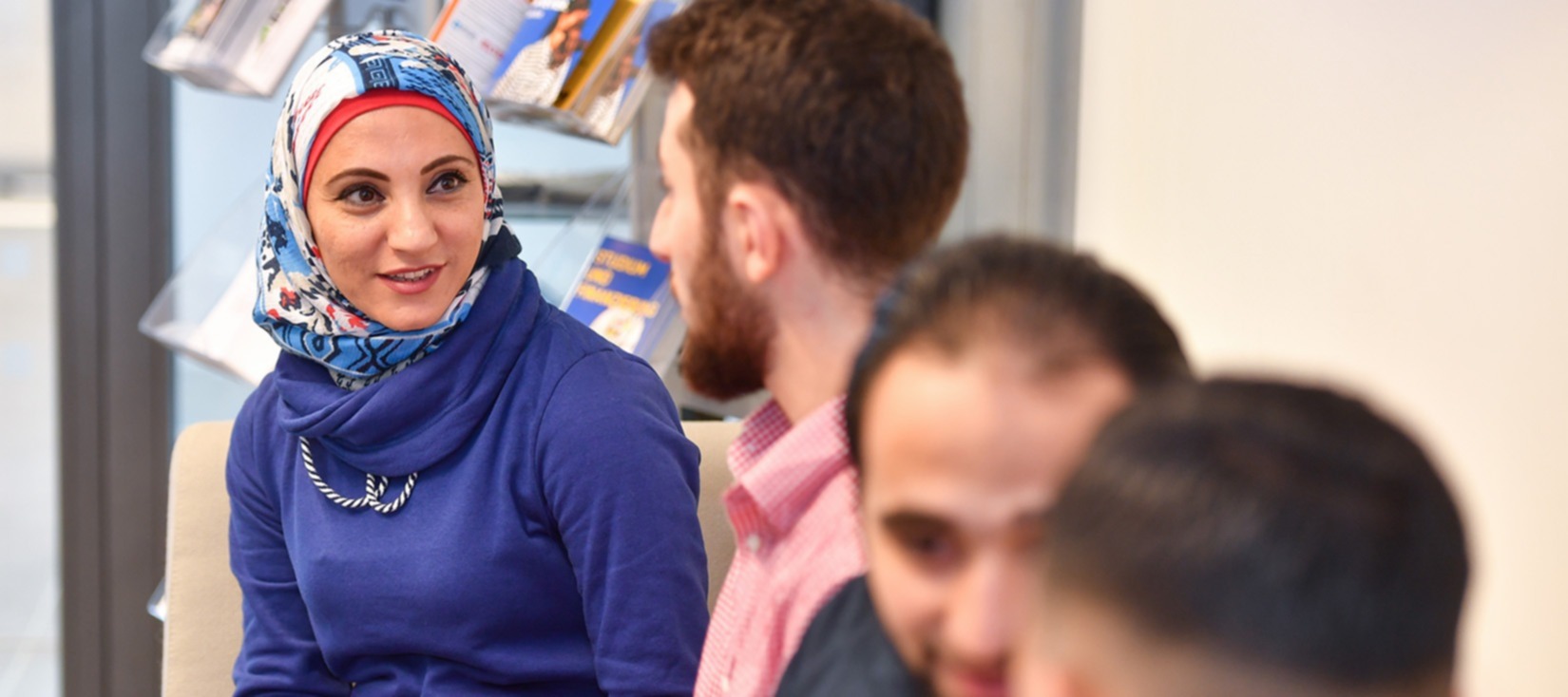 Junge Frau mit Kopftuch im Gespräch mit einem jungen Mann